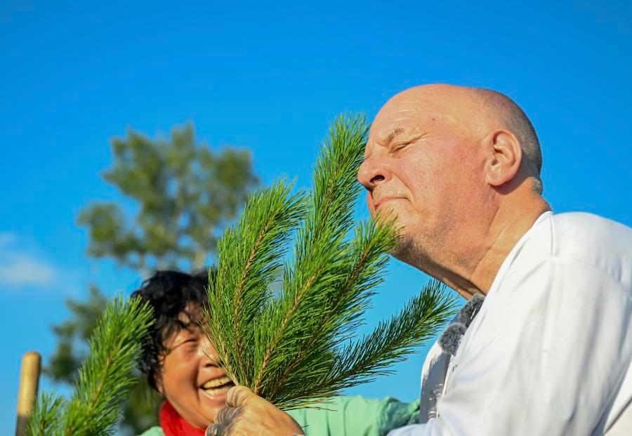 Ronald Sakolsky (R) sniffs a sapling after planting it with Yin Yuzhen in the Maowusu Sandy Land
